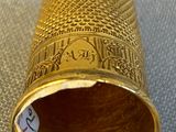 a gold thimble on a table with a price tag