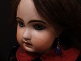 a close up of a doll with a black dress and red collar