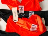 three orange and black swimsuits with tags on them on a white surface