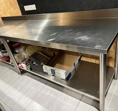 une table de travail en acier inoxydable avec une étagère en dessous