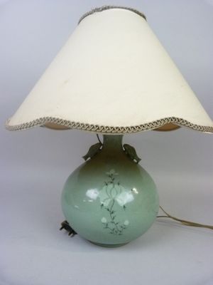 a green lamp that has a white shade on it