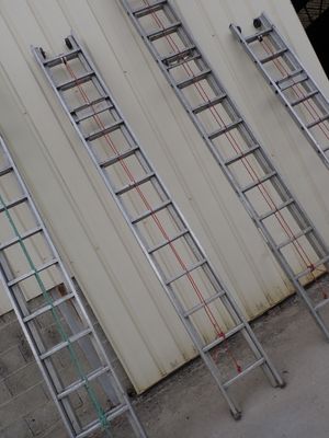 several ladders are lined up against a wall in front of a building