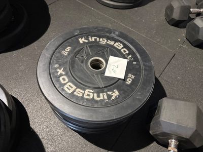 une photo montrant une plaque de poids et des haltères posés sur le sol d'une salle de sport