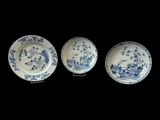 three blue and white plates with birds and flowers on them