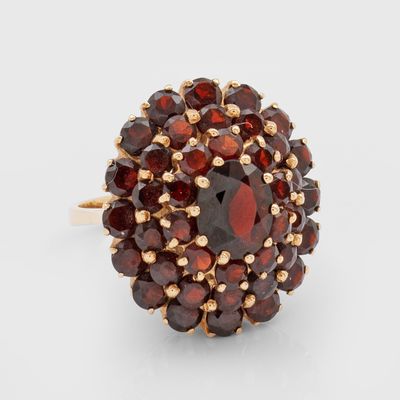 un gros plan d'une bague sertie de grenats sur un fond blanc