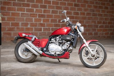 a red motorcycle parked in front of a brick wall