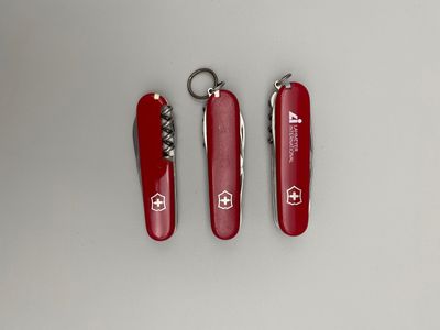 deux couteaux suisses rouges munis d'un porte-clés, posés sur une surface blanche