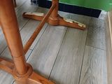 a wooden table with two legs and a green wall behind it