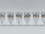 four white wine glasses with gold and blue designs on them