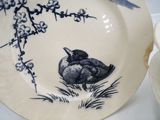 a plate with a bird on it sitting next to a cup