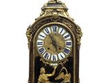 a clock that is sitting on a table with a statue on it