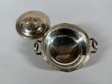 silver plated bowl with handles and a lid on a white surface