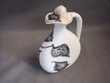 a white and black vase with a bird on top of it