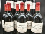 six bouteilles de vin rouge sont alignées sur une table noire