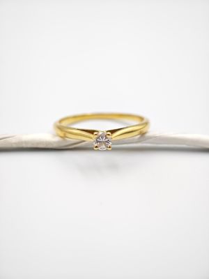 une bague de fiançailles en or ornée d'un diamant posé sur une branche