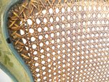 un gros plan d'une chaise en osier avec une assise verte