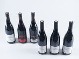 several bottles of wine are lined up in a row on a white surface