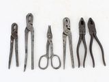 five pairs of pliers are lined up in a row on a white surface