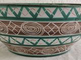 a green and brown bowl sitting on a white table