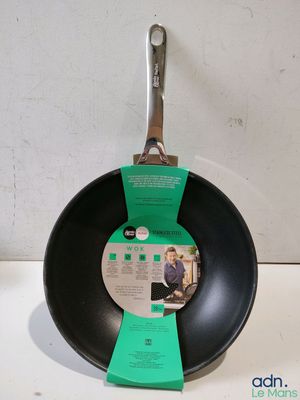 une casserole noire avec un manche vert posée sur un plan de travail