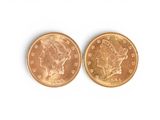 two gold coins on a white surface with a white background