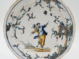 une assiette bleue et blanche sur laquelle sont représentés une femme et un oiseau