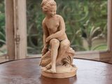 a statue of a boy sitting on a table in front of a window