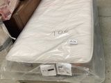 un matelas emballé dans du plastique, posé à même le sol