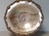 an antique silver plate on a stand on a table