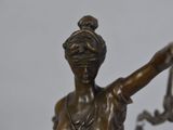 bronze statue of lady justice holding scales on a marble base