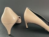 a pair of nude colored heels on a black surface