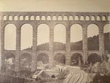 an old photo of a train going under a bridge
