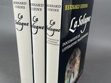 trois livres sont empilés sur une surface grise