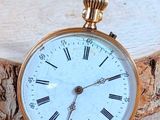 a gold pocket watch sitting on top of a piece of wood