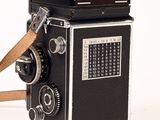 a black and white photo of a camera with a leather strap