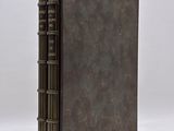 an old book with a brown cover sitting on top of a white surface