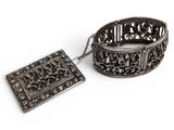 pair of antique silver bracelets and a pendant on a white background