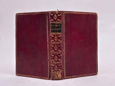 un vieux livre à la couverture rouge posé sur une surface blanche