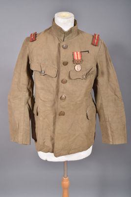 une vieille veste militaire posée sur un mannequin, ornée d'une médaille