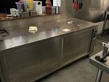un grand plan de travail en inox dans une cuisine où de nombreux couteaux sont accrochés au mur