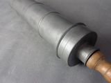 a metal object with a wooden handle on a gray surface