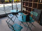 tables and chairs in front of a window with bottles of wine in the background