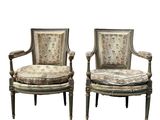 a pair of antique chairs with floral upholstered cushions