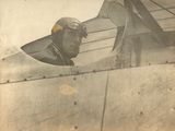 une vieille photo d'un homme portant un casque de pilote, regardant par le hublot d'un avion