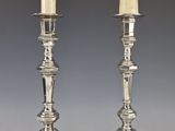 pair of silver candlesticks with candles on each of them