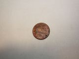 a penny sitting on a table next to a small coin