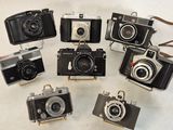 several old cameras are arranged in a circle on a white surface