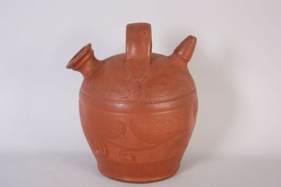 a brown vase with three handles on a white surface