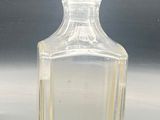 a clear glass bottle with a small amount of liquid in it