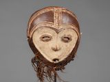 a wooden mask on a stand with a brown and white face